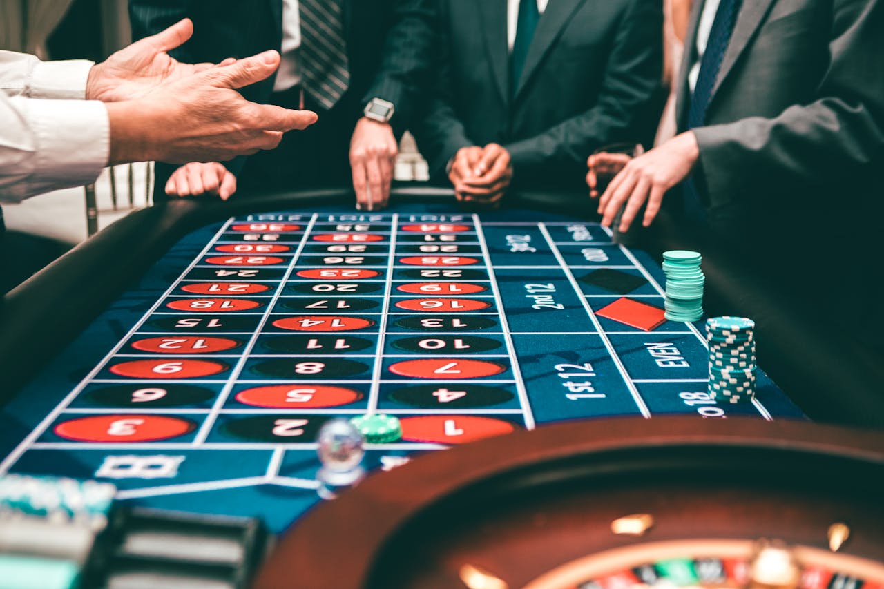 about-us-02 Group of people playing roulette, placing bets in a casino setting.