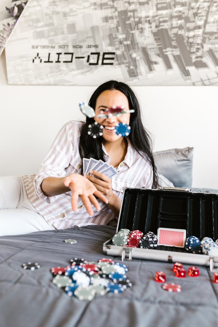 gallery-04 Woman in striped shirt playing poker on bed, tossing chips with cards and poker set.